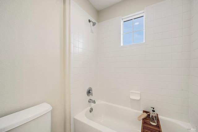 bathroom featuring bathtub / shower combination, a textured wall, and toilet