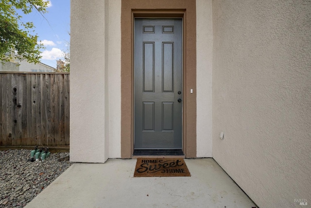 property entrance featuring fence and stucco siding