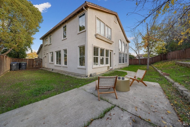 rear view of property with stucco siding, a fenced backyard, a lawn, and a patio