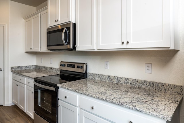 kitchen with light stone countertops, stainless steel appliances, and white cabinetry