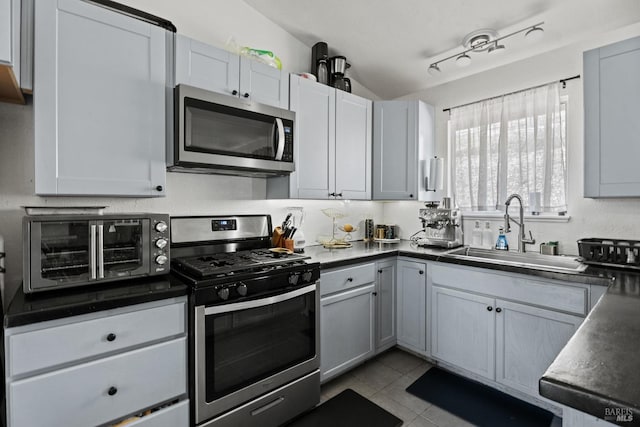 kitchen with stainless steel appliances, sink, light tile patterned floors, gray cabinets, and lofted ceiling