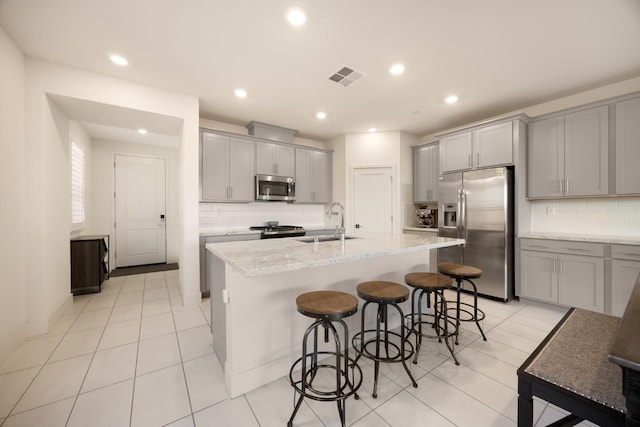 kitchen featuring stainless steel appliances, a sink, visible vents, backsplash, and gray cabinets