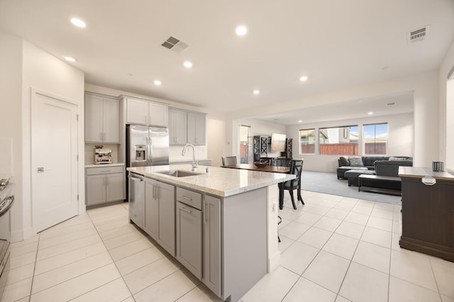 kitchen featuring stainless steel appliances, visible vents, gray cabinets, light tile patterned floors, and a sink
