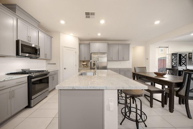kitchen with visible vents, a sink, stainless steel appliances, and gray cabinetry