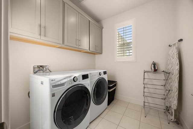 laundry room featuring washing machine and clothes dryer, baseboards, light tile patterned floors, and cabinet space