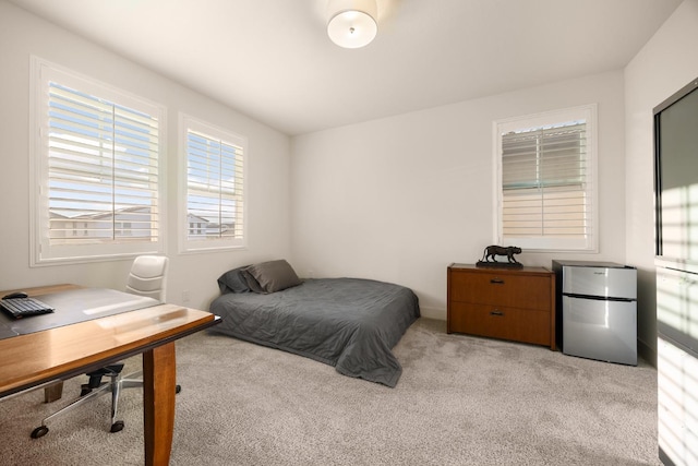 bedroom with baseboards, freestanding refrigerator, and light colored carpet