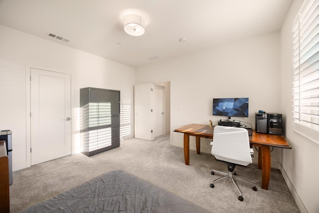 office area with visible vents, baseboards, and light carpet