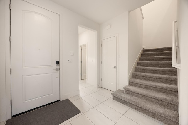 entryway featuring stairway, baseboards, and light tile patterned floors