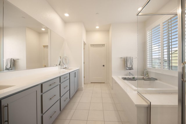 full bath with tile patterned floors, a garden tub, recessed lighting, and double vanity