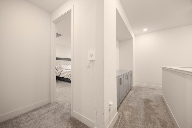 corridor featuring light colored carpet, baseboards, visible vents, and recessed lighting