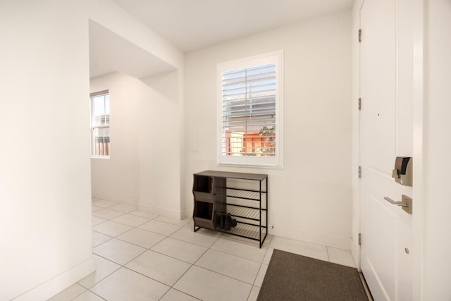 hall featuring baseboards and light tile patterned flooring