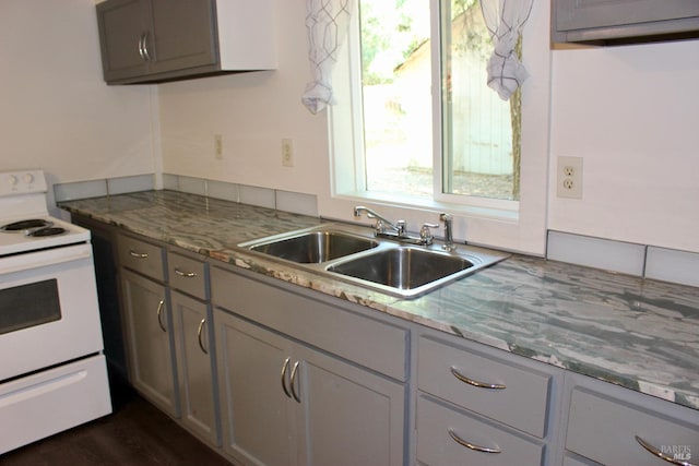 kitchen featuring gray cabinetry, white range with electric cooktop, sink, dark hardwood / wood-style floors, and light stone counters