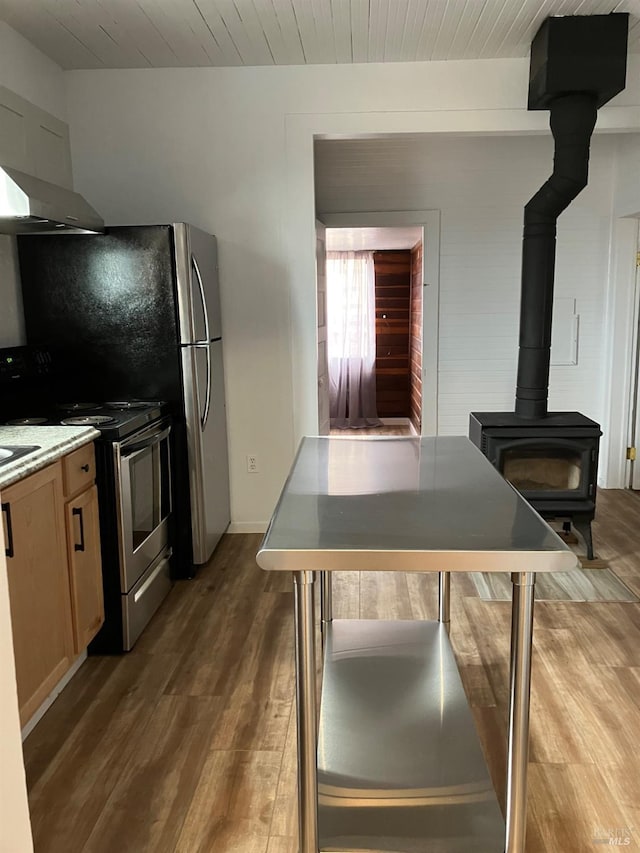 kitchen with a wood stove, wooden ceiling, stainless steel electric range, and hardwood / wood-style flooring