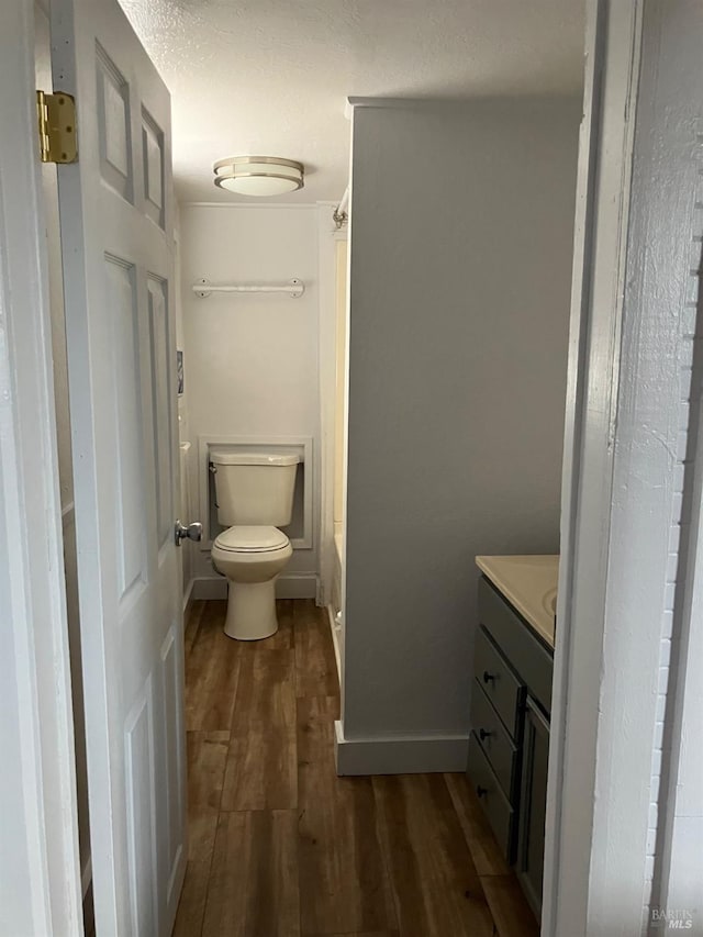 bathroom featuring a washtub, vanity, hardwood / wood-style flooring, and toilet