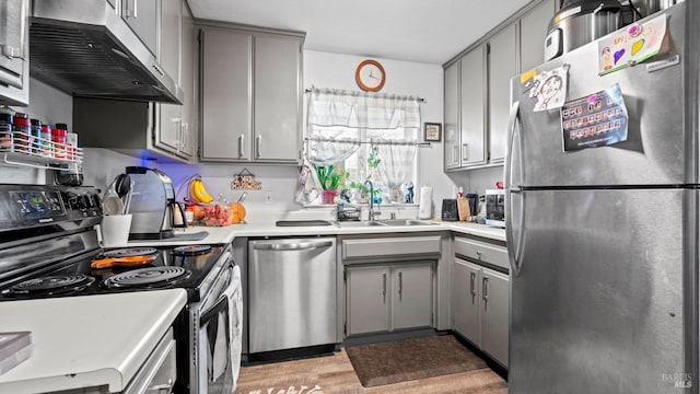 kitchen featuring ventilation hood, sink, gray cabinets, light wood-type flooring, and appliances with stainless steel finishes