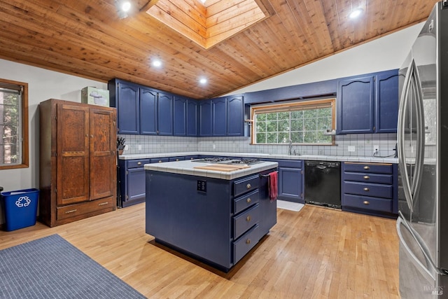 kitchen featuring lofted ceiling with skylight, sink, stainless steel appliances, blue cabinetry, and light wood-type flooring