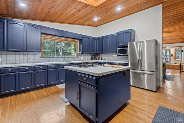 kitchen with blue cabinetry, stainless steel appliances, and lofted ceiling with skylight