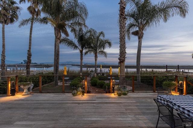 deck at dusk with a water and mountain view