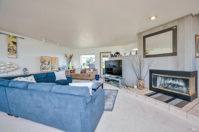 carpeted living room featuring a tile fireplace and rail lighting