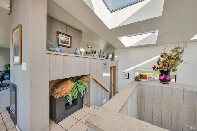 interior space with vaulted ceiling with skylight and light tile patterned floors