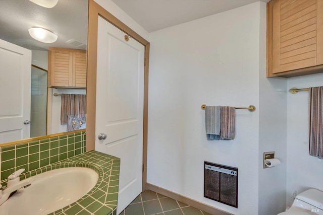 bathroom featuring heating unit, decorative backsplash, and toilet