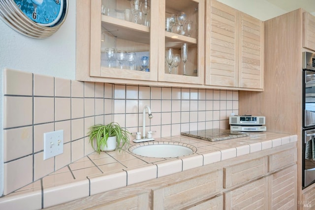 kitchen with light brown cabinets, sink, and tasteful backsplash