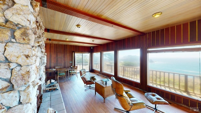 unfurnished sunroom with beam ceiling and a water view