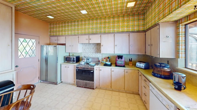 kitchen featuring stove, white dishwasher, a wealth of natural light, and refrigerator