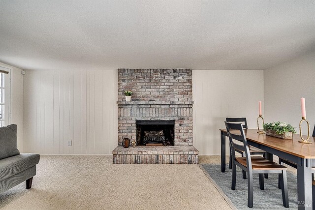 carpeted living room featuring a brick fireplace and a textured ceiling