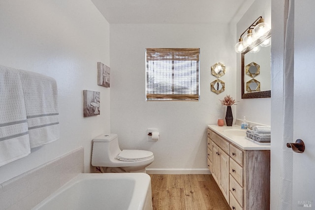 bathroom featuring a bath, vanity, hardwood / wood-style floors, and toilet