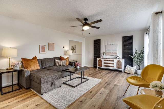 living room featuring ceiling fan, a textured ceiling, and light hardwood / wood-style flooring