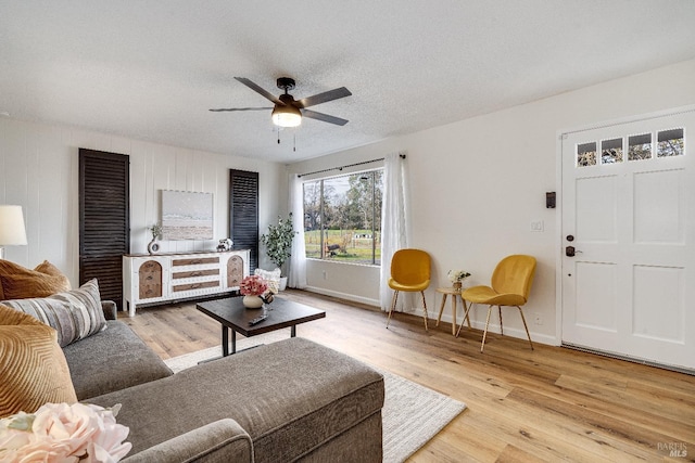 living room featuring ceiling fan, a textured ceiling, and light hardwood / wood-style flooring