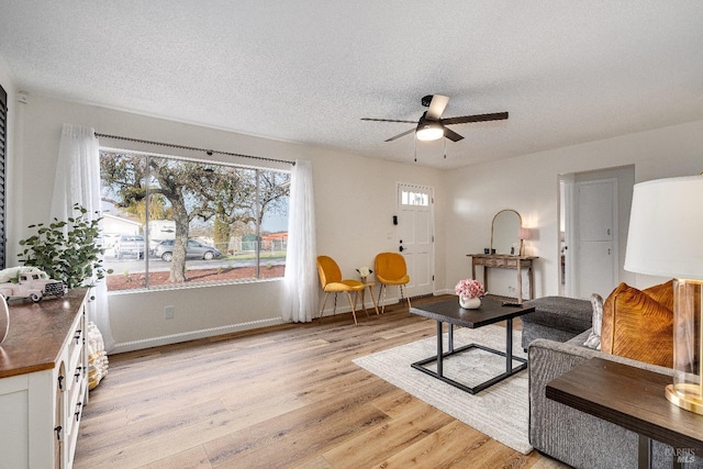 living room with ceiling fan, light hardwood / wood-style floors, and a textured ceiling