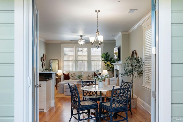 dining area with ceiling fan with notable chandelier, ornamental molding, and light hardwood / wood-style floors