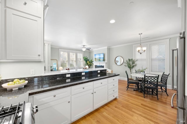 kitchen with white cabinetry, stove, ornamental molding, and dark stone counters