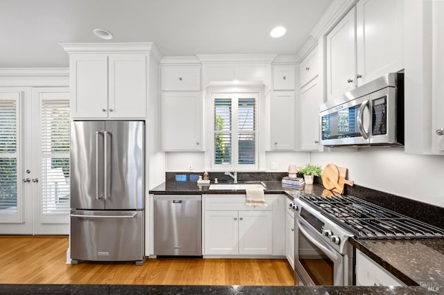 kitchen featuring sink, dark stone countertops, white cabinets, light hardwood / wood-style floors, and stainless steel appliances