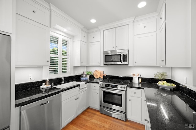 kitchen with sink, dark stone counters, white cabinets, and appliances with stainless steel finishes