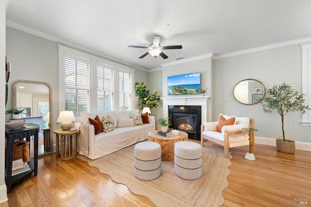 living room with light wood-type flooring, ceiling fan, and crown molding