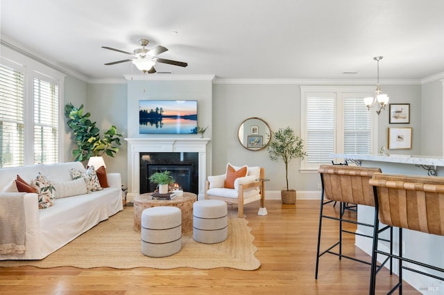 living room featuring ornamental molding, ceiling fan with notable chandelier, and light hardwood / wood-style flooring