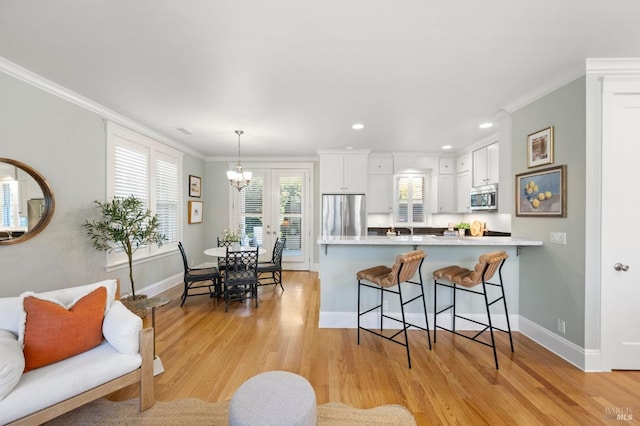 kitchen with crown molding, stainless steel appliances, light hardwood / wood-style floors, white cabinets, and kitchen peninsula