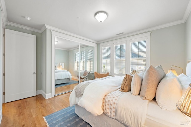 bedroom with crown molding, light hardwood / wood-style floors, and a closet