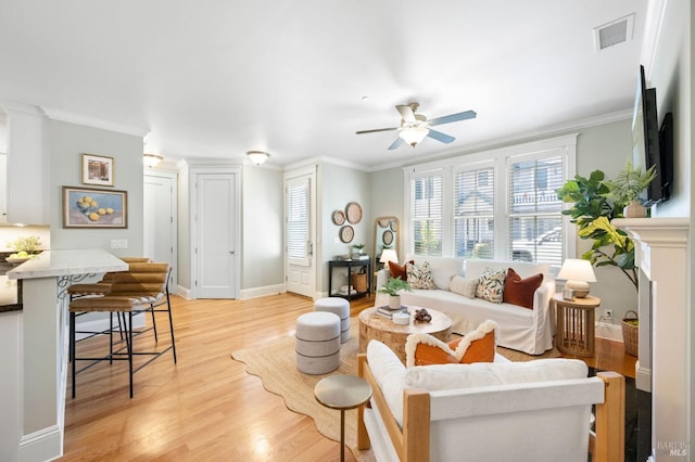 living room with crown molding, ceiling fan, and light wood-type flooring