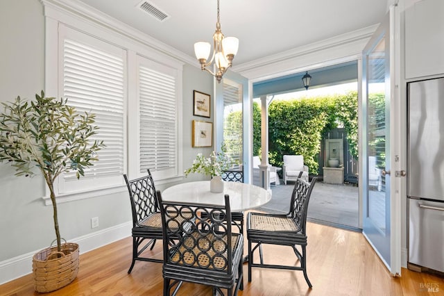 dining room featuring an inviting chandelier, crown molding, and light hardwood / wood-style flooring