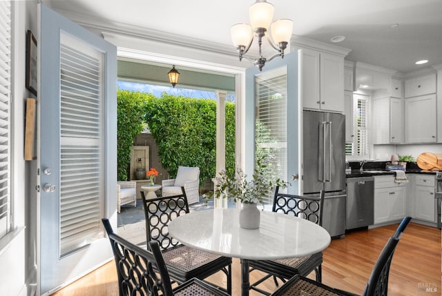 dining space featuring a notable chandelier, ornamental molding, and light wood-type flooring