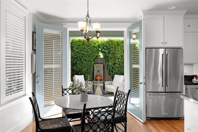 dining area with an inviting chandelier, crown molding, light hardwood / wood-style flooring, and a wealth of natural light