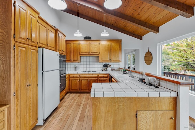 kitchen featuring light hardwood / wood-style flooring, vaulted ceiling with beams, tile counters, white fridge, and kitchen peninsula