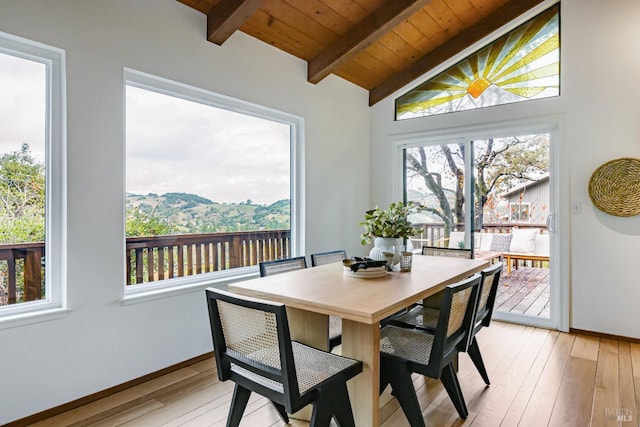 dining room with vaulted ceiling with beams, light hardwood / wood-style floors, a mountain view, and wood ceiling