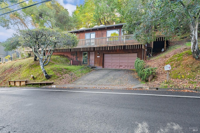rustic home featuring a wooden deck, driveway, and a garage