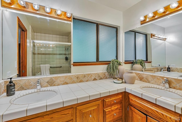 bathroom featuring double vanity, a shower stall, and a sink