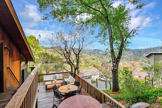 wooden deck with outdoor dining space, an outdoor living space, and a mountain view